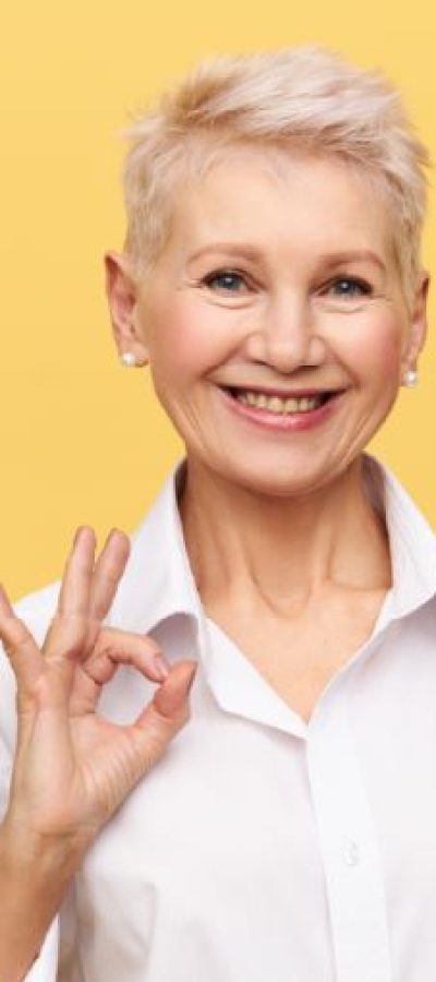 portrait-of-successful-confident-middle-aged-businesswoman-with-short-dyed-hair-with-broad-smile-making-ok-gesture-rejoicing-at-good-profitable-deal-and-great-yearly-income